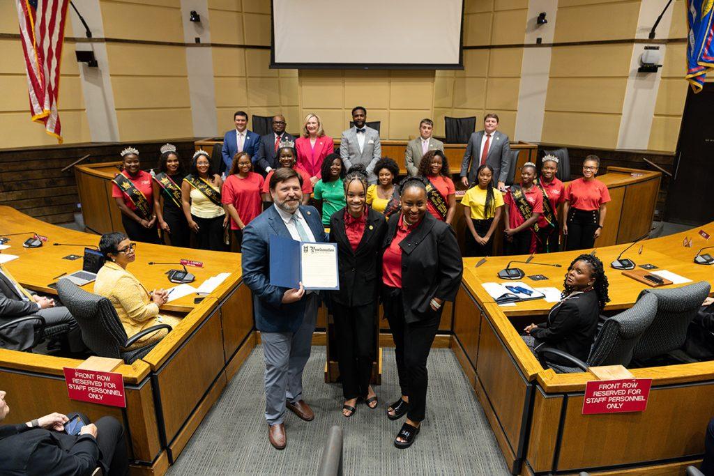 Mayor Spiro Cheriogotis and Miss Juneteenth America leadership holding the City of Mobile fifth-anniversary proclamation.